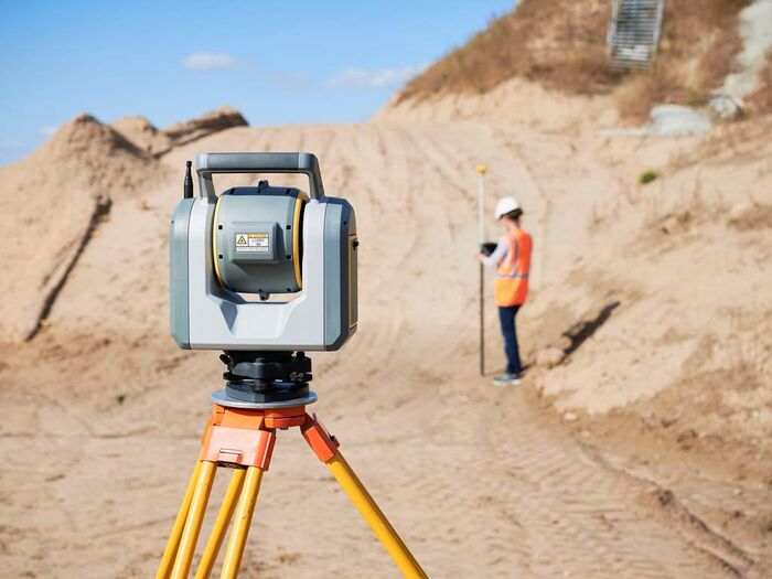Geodet s totální stanicí při zaměřování terénních úprav na staveništi